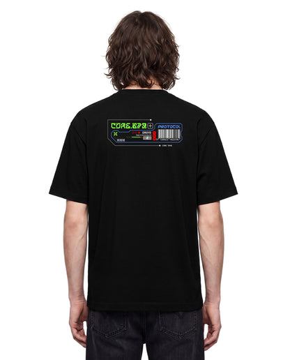 A man viewed from behind wearing a black t-shirt with a colorful retro computer terminal graphic on the upper back, paired with dark jeans against a plain white background.