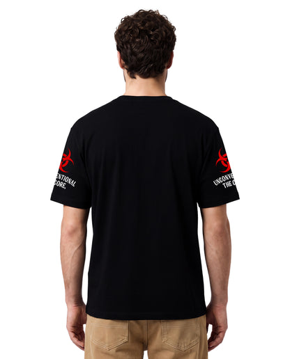 A man viewed from the back wearing a black short-sleeve t-shirt with red and white graphics on both sleeves, paired with khaki pants, against a plain white background.